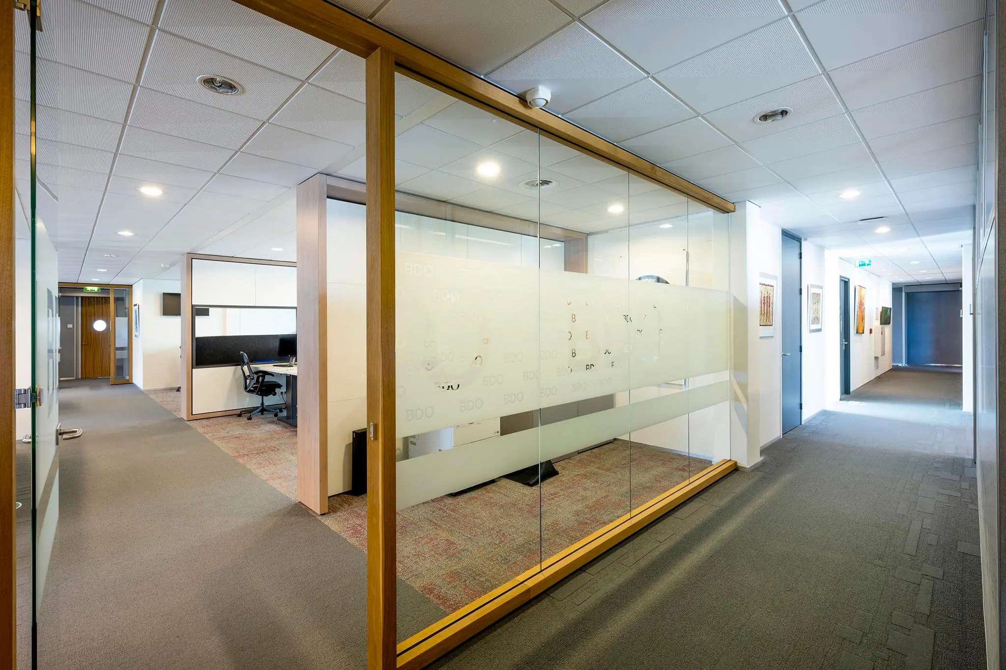 Modern kantoorinterieur aan de K.P. van der Mandelelaan met glazen wanden en werkplekken van BDO.